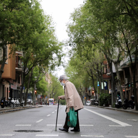 Una mujer mayor con mascarilla cruza la calle con la bolsa de la compra en Barcelona. REUTERS/Nacho Doce