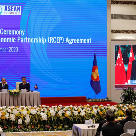 El primer ministro de Vietnam, Nguyen Xuan Phuc (izq.), con el ministro de Industria y Comercio, Tran Tuan Anh, mientras ven una pantalla que muestra al ministro de Comercio chino, Zhong Shan firmando junto al primer ministro chino Li Keqiang, el acuerdo 