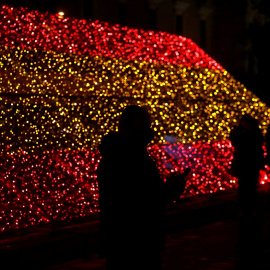 Varias personas pasan junto a la iluminación navideña colocada por el Ayuntamiento de Madrid con los colores de la bandera de España. REUTERS/Sergio Perez