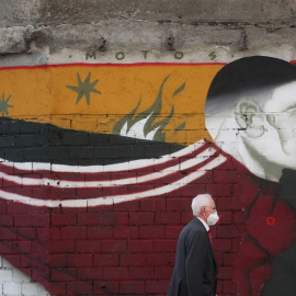 Varias personas con mascarilla pasan por delante de un graffiti en una calle de Madrid. REUTERS/Susana Vera