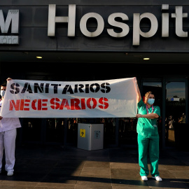 Dos trabajadores sanitarios del Hospital La Paz de Madrid sostienen una pancarta en la que reclaman más personal y medios. REUTERS/Juan Medina