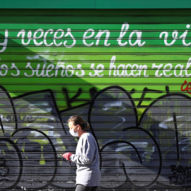 Una mujer con marcarilla pasa por delante de un comercio cerrado en la madrileña calle de Alcalá. REUTERS/Sergio Perez
