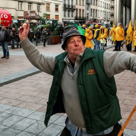 En manifestante lanza un huevo dirigido a agentes de policía mientras los agricultores de Bélgica y otros países europeos usan sus tractores para bloquear el exterior del Parlamento Europeo, en Bruselas, mientras protestan por las presiones de precios,