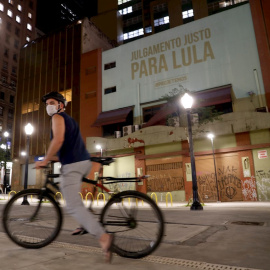 Un ciclista pasa frente a una proyección en favor del expresidente Luiz Inácio Lula da Silva, en el centro de Sao Paulo (Brasil). EFE/Fernando Bizerra