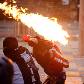 Un hombre se cubre del fuego durante un enfrentamiento con la Policía en el centro de Bogotá (Colombia).- EFE