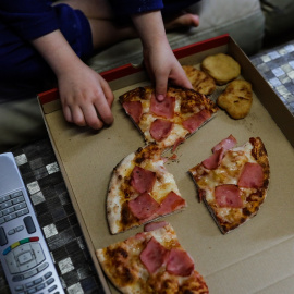 Un niño come un trozo de pizza del menú infantil de Telepizza en su casa. E.P./Jesús Hellín