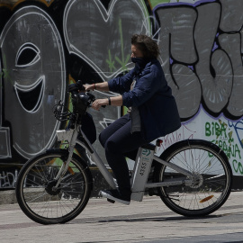 Una mujer protegida con mascarilla monta en una bicicleta de BiciMAD. E.P./Eduardo Parra