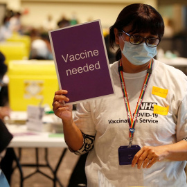 Una voluntaria para la vacunación en Londres sostiene un cartel que dice "vacunación necesaria". REUTERS/Peter Nicholls