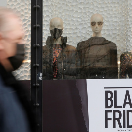 Un hombre con mascarilla pasa delante de una tienda en Kiev (Ucrania) con anuncios de ofertas por el 'Black Friday'. REUTERS/Valentyn Ogirenko