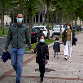 Un matrimonio con sus hijos, todos con mascarilla, dando un paseo en Bilbao. REUTERS/Vincent West