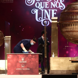 Una empleada limpia la mesa del sorteo de Lotería de Navidad para que se cumplan todas las medidas de higiene. E.P./Eduardo Parra