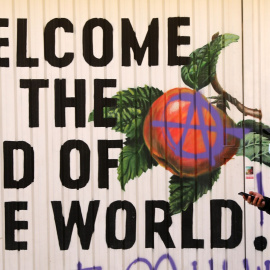 Un joven con mascarilla pasa delante de una pintada en una calle de Madrid. REUTERS/Sergio Perez