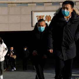 Varias personas con mascarilla salen de una boca de metro en Pekín. REUTERS/Tingshu Wang
