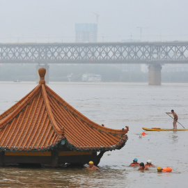 Varias personas nadan cerca de un pabellón parcialmente sumergido en las aguas del río Yangtze, tras las fuertes lluvias en Wuhan, provincia de Hubei (China). REUTERS