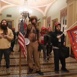 En el centro de la imagen, vestido con pieles, Jake Angeli, miembro del movimiento de teorías de la conspiración Qanon, y que se hace llamar 'Yellowstone Wolf', con otros seguidores de Donald Trump, en su asalto al Capitolio de EEUU, en Washington. AFP/
