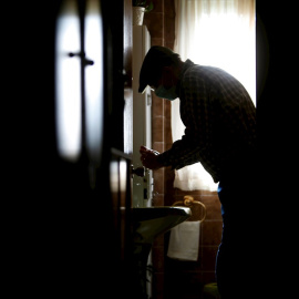 Un hombre se lava las manos en su casa del concello coruñés de Pontedeume, con la mascarilla puesta por recomendación de su médico de cabecera. EFE/Cabalar