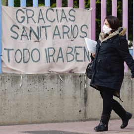 Una mujer embarazada pasa por delante de una pancarta colocada en la valla de un hospital. EFE/NACHO GALLEGO