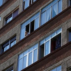 Una mujer mira desde una de las ventanas de su vivienda en Bilbao. REUTERS/Vincent West