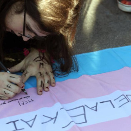 Una joven firma la bandera transexual durante una concentración convocada por la asociación Chrysallis. EFE