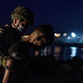  Un soldado del Ejército de Tierra conduce a un inmigrante tras salir del agua en la playa de El Tarajal, en una jornada en la que Ceuta espera en calma tensa una nueva jornada tras la entrada masiva de 8.000 personas desde el lunes- EFE/Brais Lorenzo