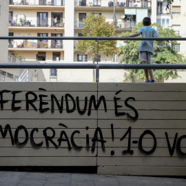  Un niño frente a un grafiti leyendo en catalán "¡Referéndum es democracia! 1-O (1 de octubre) vota" en el barrio de Gracia de Barcelona, el 30 de septiembre de 2017.- AFP