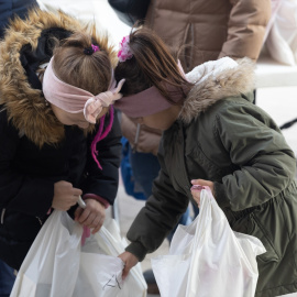 Dos niñas ucranianas que están en España como refugiadas sujetan bolsas con regalos, en la Plaza San Amaro, a 18 de diciembre de 2022, en Madrid (España). EUROPA PRESS