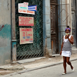  Dos mujeres caminan junto a varios carteles expuestos en la ventana de una casa en una calle de La Habana, Cuba, este martes 20 de julio del 2021. EFE/ Ernesto Mastrascusa