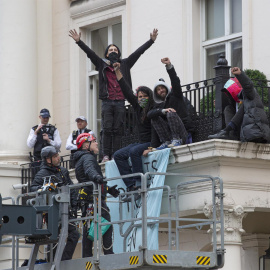  Agentes de policía (L) usan un vehículo equipado con un selector de cerezas para acercarse a un grupo de ocupantes ilegales en el borde de un balcón después de que ocuparon una mansión en Belgrave Square, en Londres, Gran Bretaña, el 14 de marzo de