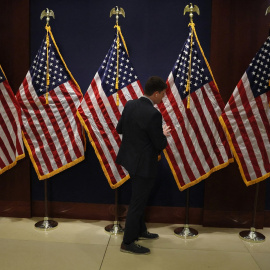 Un miembro del personal del Capitolio coloca las banderas de EEUU para la recepción de los nuevos congresistas de las recientes elecciones de 'midterm'. REUTERS/Leah Millis