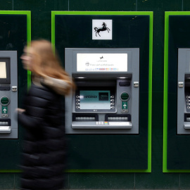 Una mujer pasa junto a los cajeros automáticos de una sucursal de Lloyds Bank en Manchester. REUTERS/Phil Noble