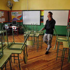 Un docente habla por su teléfono móvil en un aula desierta en un colegio público de Madrid.. - EFE