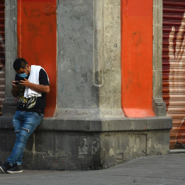 Un hombre observa su teléfono móvil en una calle del centro histórico de Ciudad de México. México extenderá las medidas de distanciamiento social hasta el 30 de mayo. - EFE
