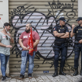  Dos hombres y dos agentes de la Policía Nacional durante una manifestación frente a la sede de la Confederación Empresarial de la Comunitat Valenciana (CEV) para exigir salarios dignos, a 6 de julio de 2022, en Valencia, Comunidad Valenciana (España)