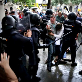  Un hombre intenta proteger a una mujer de los porrazos de la Policía Nacional, el 1 de octubre de 2017. - Jordi Play / ACN
