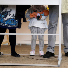 Una niña, entre sus padres en una cabina electoral en los pasados comicios del 28-A. REUTERS/Eloy Alonso 