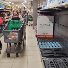 Una cliente con mascarilla pasa junto a estantes vacíos de papel higiénico en un supermercado de Madrid. /EFE