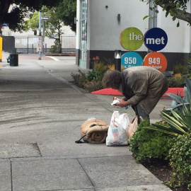 Un indigente de mediana edad comiendo en mitad de una céntrica calle de Los Ángeles. / Aitana Vargas