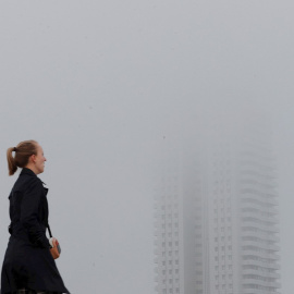 Una persona pasa junto a un edificio envuelto en niebla en Valencia. EFE