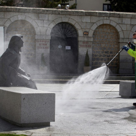 Un operario trabajando en labores de desinfección junto a la escultura de Santa Teresa de Jesús, este sábado en Ávila, durante la quinta semana de confinamiento debido al estado de alarma decretado por el gobierno para frenar la pandemia del COVID 19.