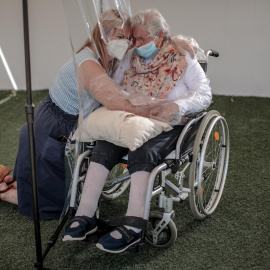 Una interna en una residencia de mayores en València abraza a su hija a través de un plástico habilitado para que los familiares se puedan dar su primer abrazo desde hace tres meses. - EFE/Biel Aliño