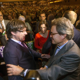 El presidente de la Generalitat Carles Puigdemont, saluda al expresidente Artur Mas en presencia de la presidenta del parlamento catalán, Carme Forcadell. - EFE