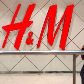 Una mujer, caminando junto al logotipo de H&M. /EFE