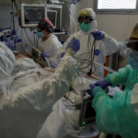 Personal sanitario totalmente protegido atiende a un paciente ingresado en la Unidad de Cuidados Intensivos del Hospital Infanta Sofía en San Sebastián de los Reyes (Madrid). Europa Press / Eduardo Parra