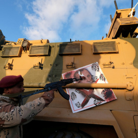 Un miembro del Ejército Nacional de Libia (LNA) comandado por Khalifa Haftar, apunta su arma a la imagen del presidente turco Tayyip Erdogan colgado de un vehículo blindado militar turco en Benghazi, Libia. REUTERS / Esam Omran Al-Fetori