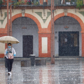 Dos mujeres con mascarillas y paraguas caminan por Córdoba. EFE/Salas
