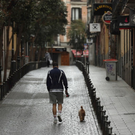 Un hombre pase a su perro en el madrileño barrio de Malasaña. EFE/Kiko Huesca