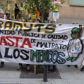 Varias personas con una pancarta en la que se lee: 'Sanidad pública de calidad, basta de maltrato a los médicos' durante una concentración enmarcada en el inicio del modelo de atención urgente extrahospitalaria, frente a la consejería de Sanidad, a 7