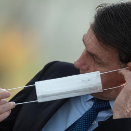 El presidente de Brasil, Jair Bolsonaro, se pone una mascarilla durante una ceremonia oficial, el 9 de junio de 2020, en el Palacio do Alvorada. EFE/ Joédson Alves.