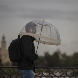 Un hombre camina bajo la lluvia protegido bajo su paraguas durante un chubasco. / Europa Press / Archivo
