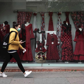 22/04/2020.- Una mujer con mascarilla camina junto a un escaparate de una tienda. / EFE - RAFA ALCAIDE